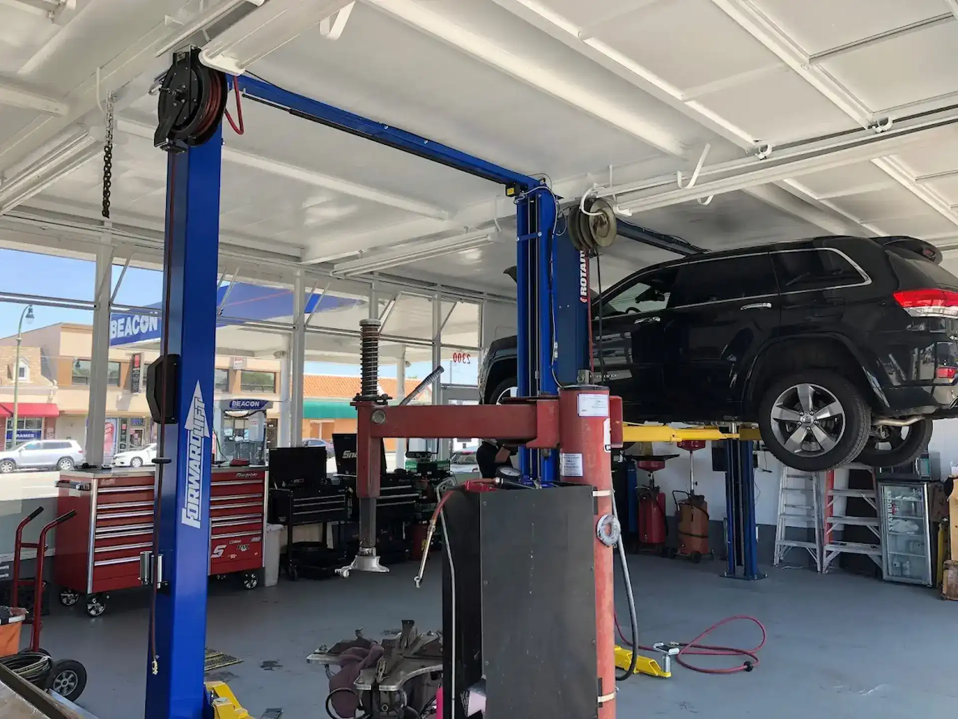 Vehicle on lift at Beacon Auto Care San Mateo during suspension inspection — Jeep Grand Cherokee in shop bay